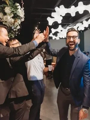 A group in suits laughing and sharing high-fives at an evening event
